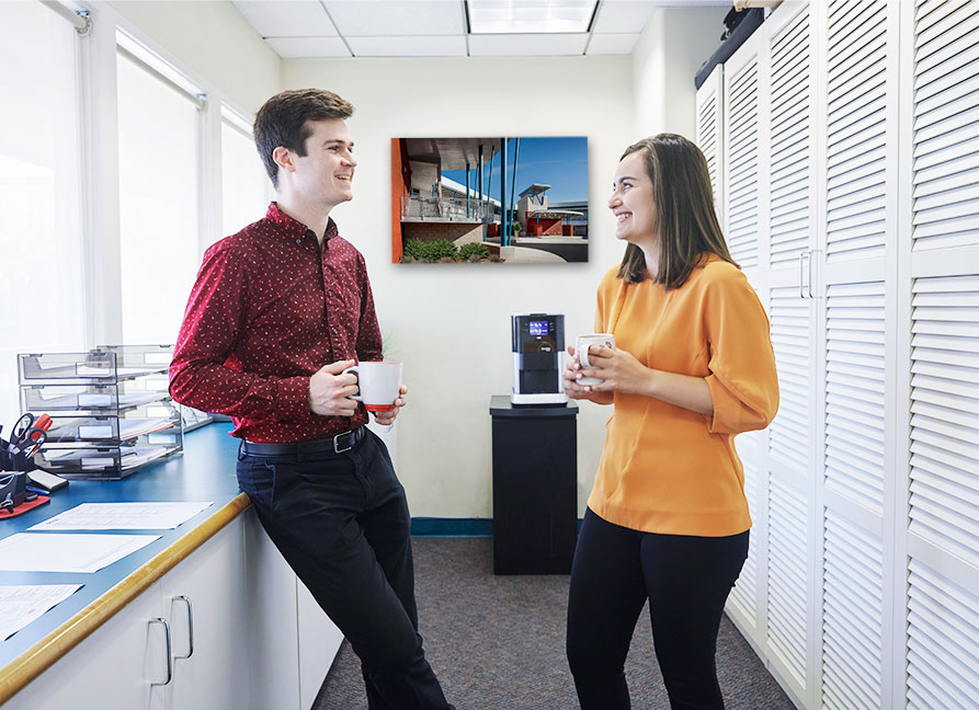 WWA Culture Breakroom Photo two people standing talking and drinking coffee